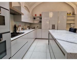 a kitchen with white cabinets and a marble counter top at Victoria Square in London
