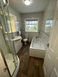a bathroom with a tub and a sink and a toilet at Lydney House Swaffham Sleeps 22 in Swaffham