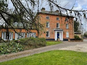 an old brick building with white windows and a driveway at Lydney House Swaffham Sleeps 22 in Swaffham