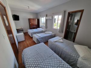 um quarto com três camas e um espelho em Hotel Hermann em Blumenau