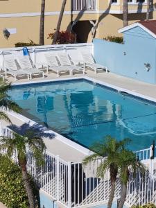 a swimming pool with chairs and palm trees at Silver Surf Gulf Beach Resort in Bradenton Beach