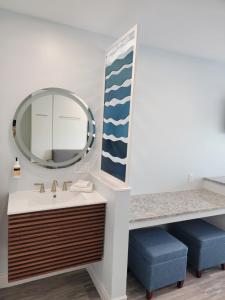 a bathroom with a sink and a mirror and two blue stools at Silver Surf Gulf Beach Resort in Bradenton Beach