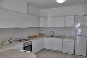 cocina con armarios blancos y nevera blanca en Villa V2 Duplex - Vilamoura Tennis, en Quarteira