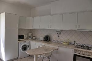 una cocina con armarios blancos y una mesa. en Villa V2 Duplex - Vilamoura Tennis, en Quarteira