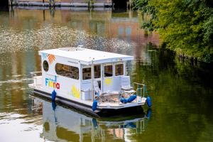 柏林Hausboot FIONA im Yachthafen Berlin-Schmöckwitz auf der Spree und dem Müggelsee von Anfang April bis Ende Oktober的漂浮在水面上的白色小船