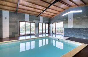 einen Pool mit blauem Wasser in einem Zimmer mit Fenstern in der Unterkunft Luxury Valdeorras in Valdegodos