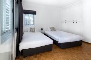 2 camas en una habitación con paredes blancas y ventana en Urban Condo 12 - 2 Bdr en Nicosia