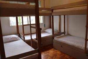 um quarto com 3 beliches e lençóis brancos em Mondo Verde Hostel em São Paulo