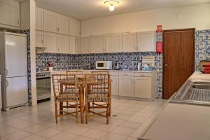 a kitchen with white cabinets and a table and chairs at Casa da Palmeira, pool & soccer pitch in Vilamoura