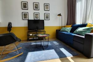 ein Wohnzimmer mit einem blauen Sofa und einem TV in der Unterkunft La verrière sur cour #L6 in Grenoble