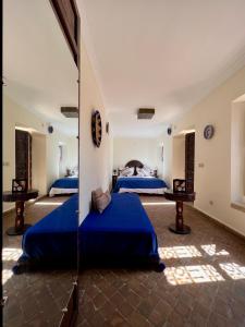 two beds in a room with blue sheets at Riad Sassa Finda in Marrakesh