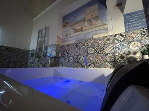a bathroom with a tub with a tiled wall at Relaxing Rooms in Pulsano
