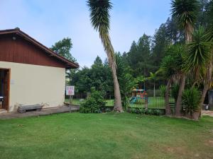 um quintal com duas palmeiras e um parque infantil em LarDoceFesta Home em Pedra Azul