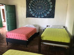 2 Betten in einem Zimmer mit Wandgemälde in der Unterkunft Nacuma Garden Hostel - Casa Nacuma in Barichara