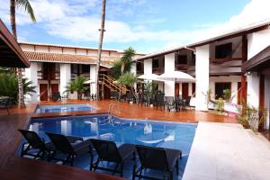 a resort with a pool and chairs and a building at Flamingo Beach - Rede Soberano in Porto Seguro