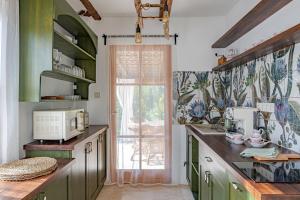 une cuisine avec des placards verts et une fenêtre dans l'établissement Casa Elisabetta Apartmanház, à Gárdony