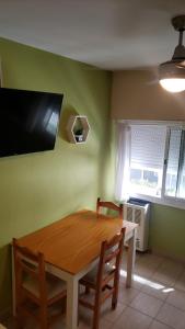 mesa de comedor con 2 sillas y TV en la pared en Excelente monoambiente completo, funcional y muy cómodo - Zona "Aldrey" en Mar del Plata