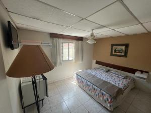 Un dormitorio con una cama y una lámpara. en Travessa 12 - Suítes centro de Serra Negra - SP en Serra Negra