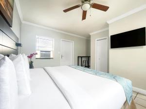 a bedroom with a white bed with a ceiling fan at Greniers in Hollywood
