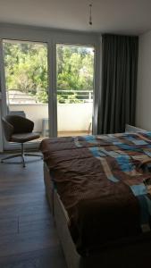 a bedroom with a bed and a chair and windows at TopFloor Ohrid in Ohrid