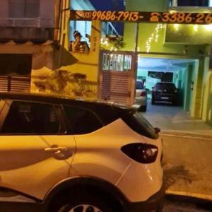 biały samochód zaparkowany przed budynkiem w obiekcie Pousada Reis Guarujá w mieście Guarujá