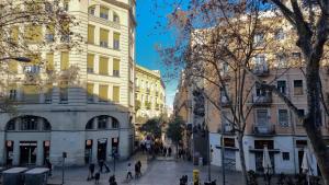 una via cittadina con edifici e persone che camminano per strada di Paraiso Hostel a Barcellona
