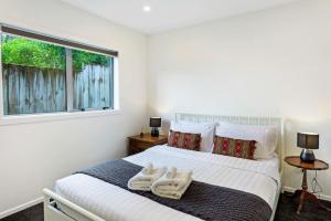 1 dormitorio con 1 cama con 2 toallas en Cascade Cottage with Parking and Wi-Fi, en Auckland