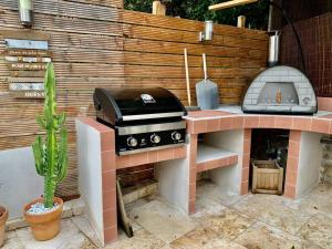 a outdoor kitchen with a grill and a pizza oven at La Reposée, bas de villa en plein cœur de Vence in Vence