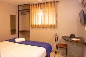 a room with a bed and a desk and a table at Hotel Montana Aeroporto in Brasilia