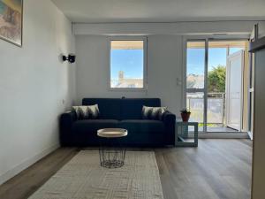 a living room with a blue couch and a table at Plage, piscine, terrasse & centre-ville à Quiberon in Quiberon