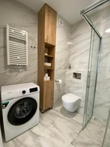 a bathroom with a washing machine and a toilet at Apartamenty Klifowa Rewal - Strefa Rekreacji in Rewal