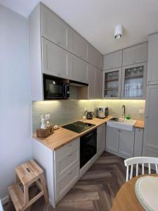 a kitchen with white cabinets and a wooden floor at Apartamenty Klifowa Rewal - Strefa Rekreacji in Rewal