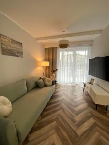 a living room with a green couch and a desk at Apartamenty Klifowa Rewal - Strefa Rekreacji in Rewal