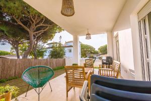 a patio with chairs and tables and a tree at Chalet individual en el Rompido urb Urverosa in El Rompido
