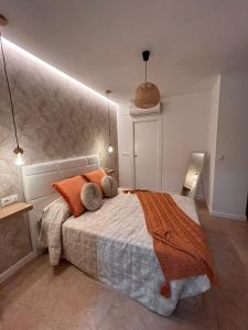 a bedroom with a large bed with orange pillows at Apartamentos Esencia in Ronda