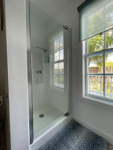 a bathroom with a shower and two windows at The Paddock House at Blanco Texas in Blanco
