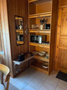eine Küche mit Holzwänden, Holzregalen und einer Mikrowelle in der Unterkunft Majatalo Wanha-Pirtti in Iitti