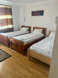 two twin beds in a room with wooden floors at Pensiunea Oșencuța in Talmesch