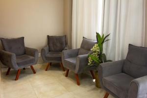 a waiting room with three chairs and a vase of flowers at Europa Hotel Brasília by Bsb Inn in Taguatinga