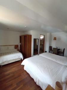 a bedroom with two white beds and a wooden floor at La Aurora in Huaraz