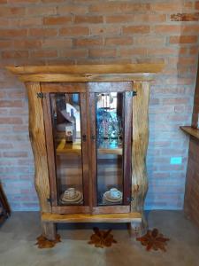 a wooden cabinet with glass doors in front of a brick wall at Chalés Santa Luzia in Santo Antônio do Pinhal