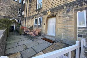 a patio with two chairs next to a brick building at The Ebor Suite a cosy apartment in Haworth in Haworth