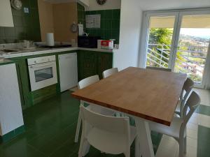 uma cozinha com uma mesa de madeira e cadeiras brancas em Casa Buenavista Villasimius em Villasimius