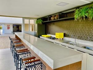 a kitchen with a long counter with chairs at PUERTO VENTURA Flat - Cabo Branco by PenareiaTurBr in João Pessoa