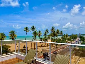 d'un balcon avec vue sur la plage et les palmiers. dans l'établissement PUERTO VENTURA Flat - Cabo Branco by PenareiaTurBr, à João Pessoa