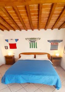 sypialnia z niebieskim łóżkiem i koszulkami na ścianie w obiekcie San Martino - Casa Landi w mieście Castellina in Chianti