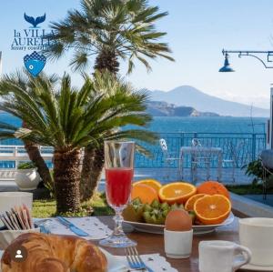 a table with a plate of fruit and a glass of juice at LA VILLA AURELIA in Bacoli