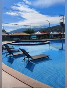 una gran piscina con dos bancos. en Praia dos Anjos Residence Clube, en Arraial do Cabo