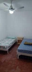 two beds in a room with a ceiling fan at Casa Rivadavia 1535 in San Pedro
