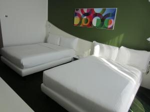 a room with two beds and a couch and a painting at Idea Hotel Milano Malpensa Airport in Case Nuove